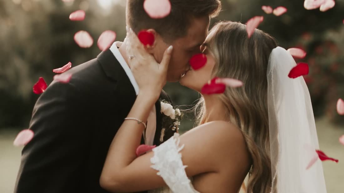 Couple kissing under falling rose petals