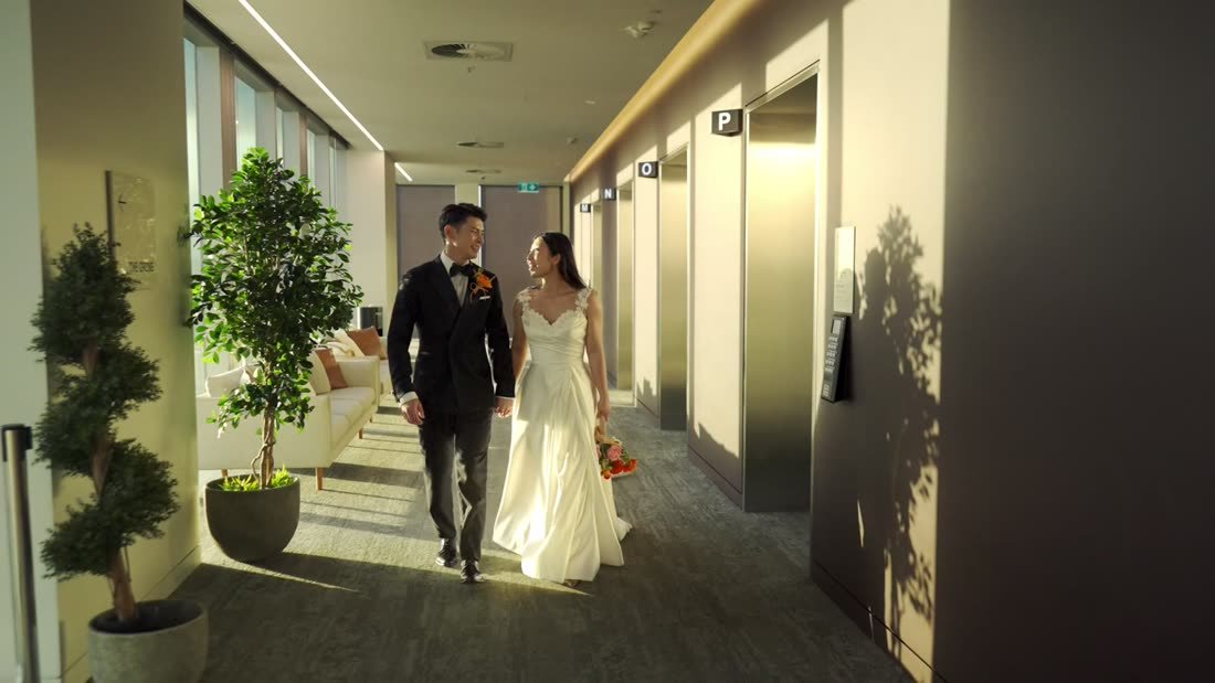 Couple walking hand in hand down a hotel hallway
